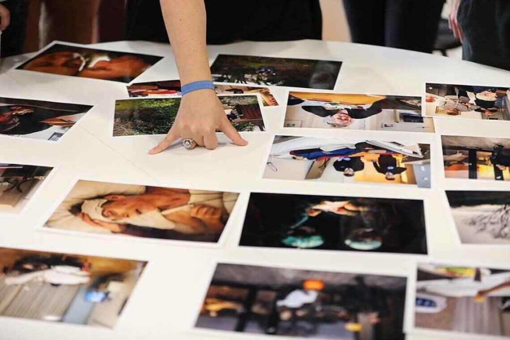 A collection of printed photographs being arranged on a table, showcasing an impressive art portfolio for review.